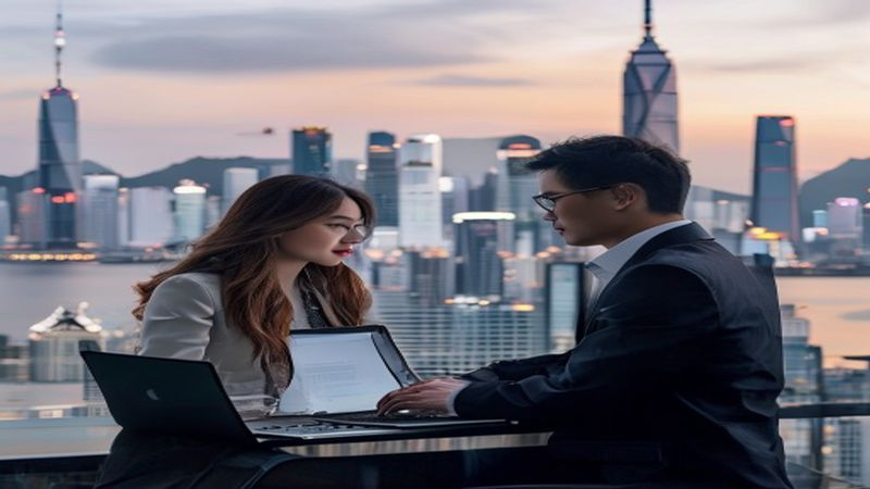 Professional digital nomad working on a laptop with a Hong Kong skyline in the background