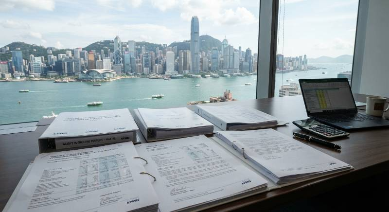 Hong Kong financial district skyline with corporate audit documents